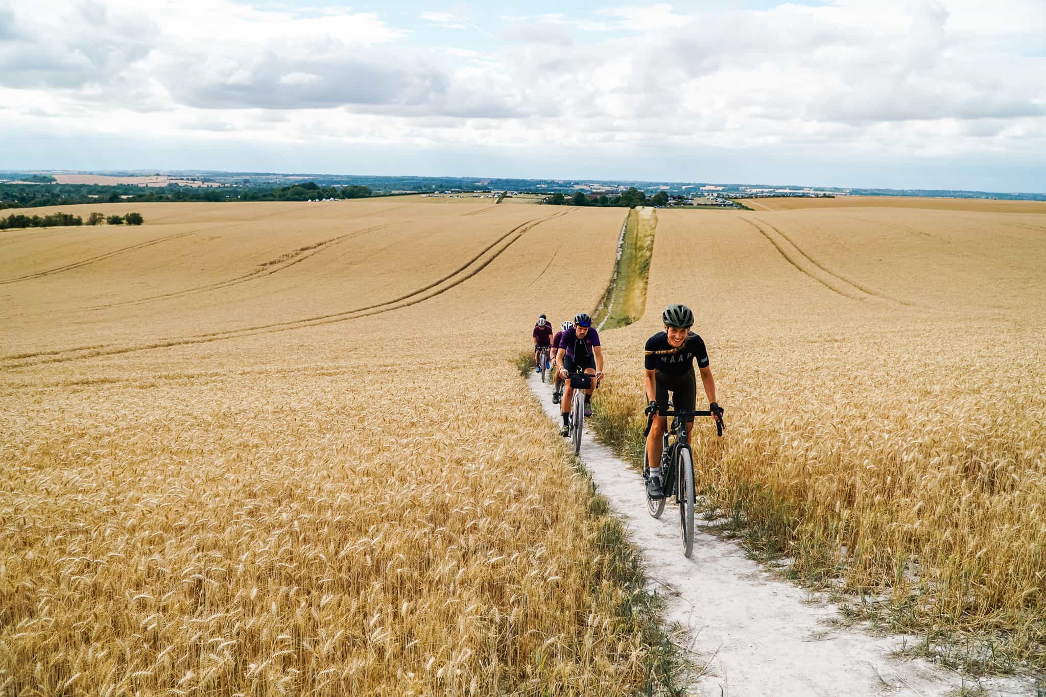 A group of people gravel riding through a wheat field.