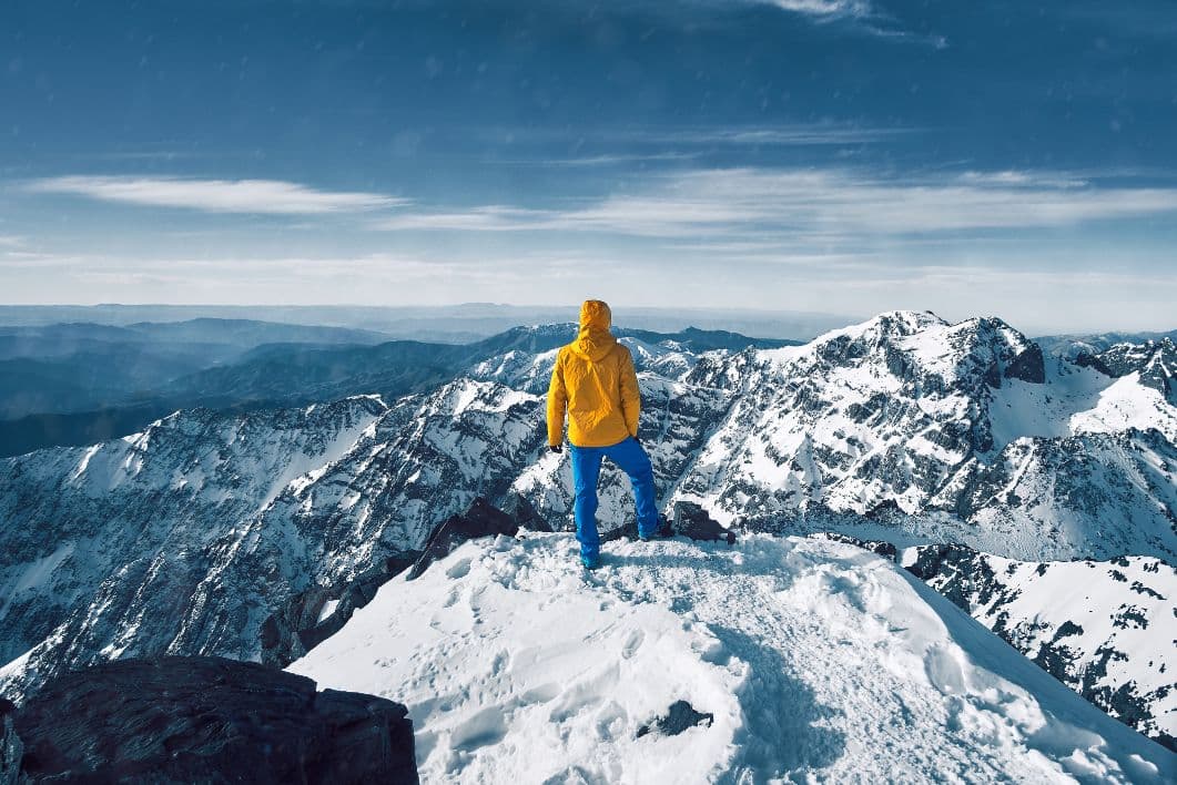 Man stands atop Toubkal looking out over the Atlas Mountains in winter. Photo: Getty