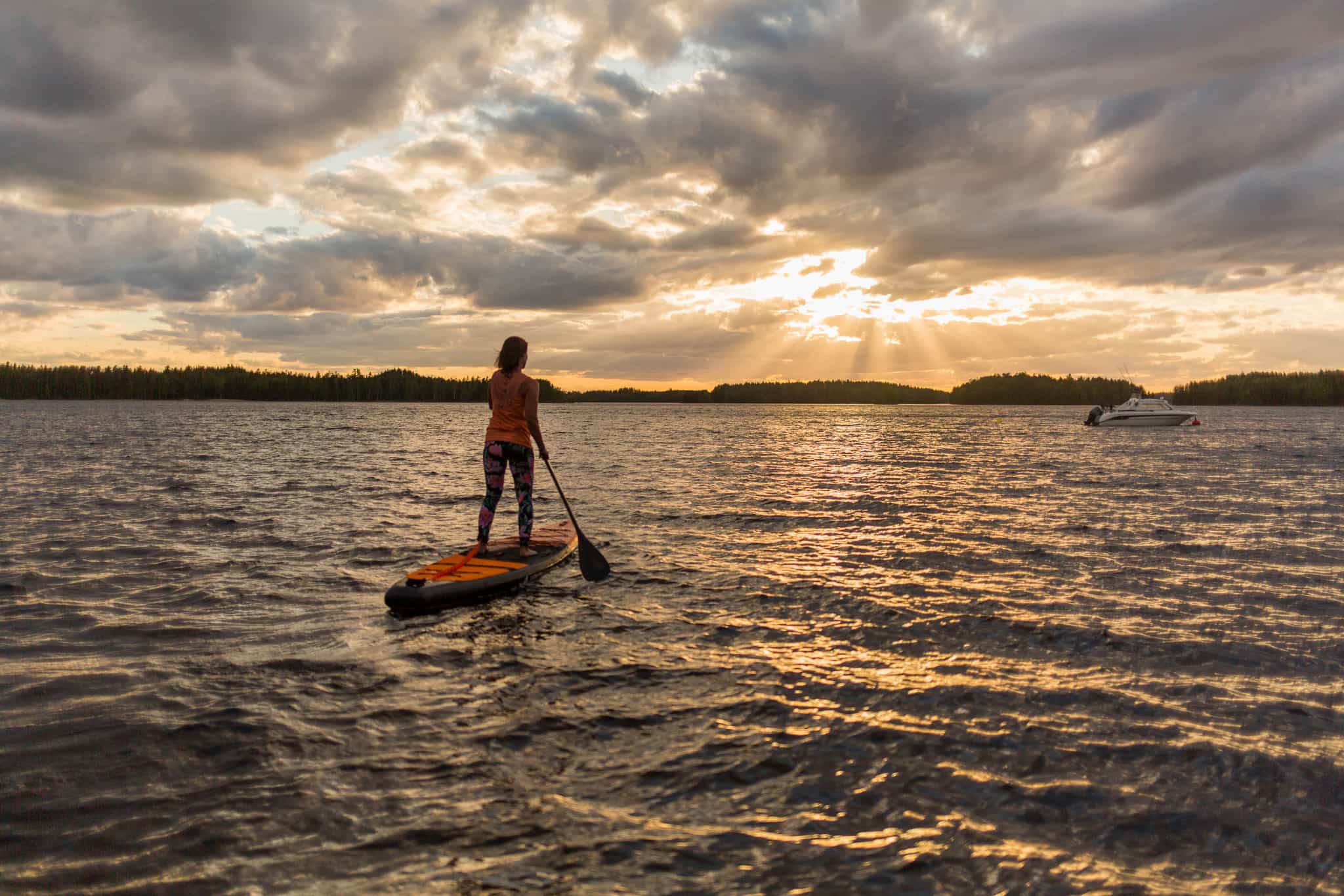 A woman paddle-boarding on Lake Saimaa at sunset
