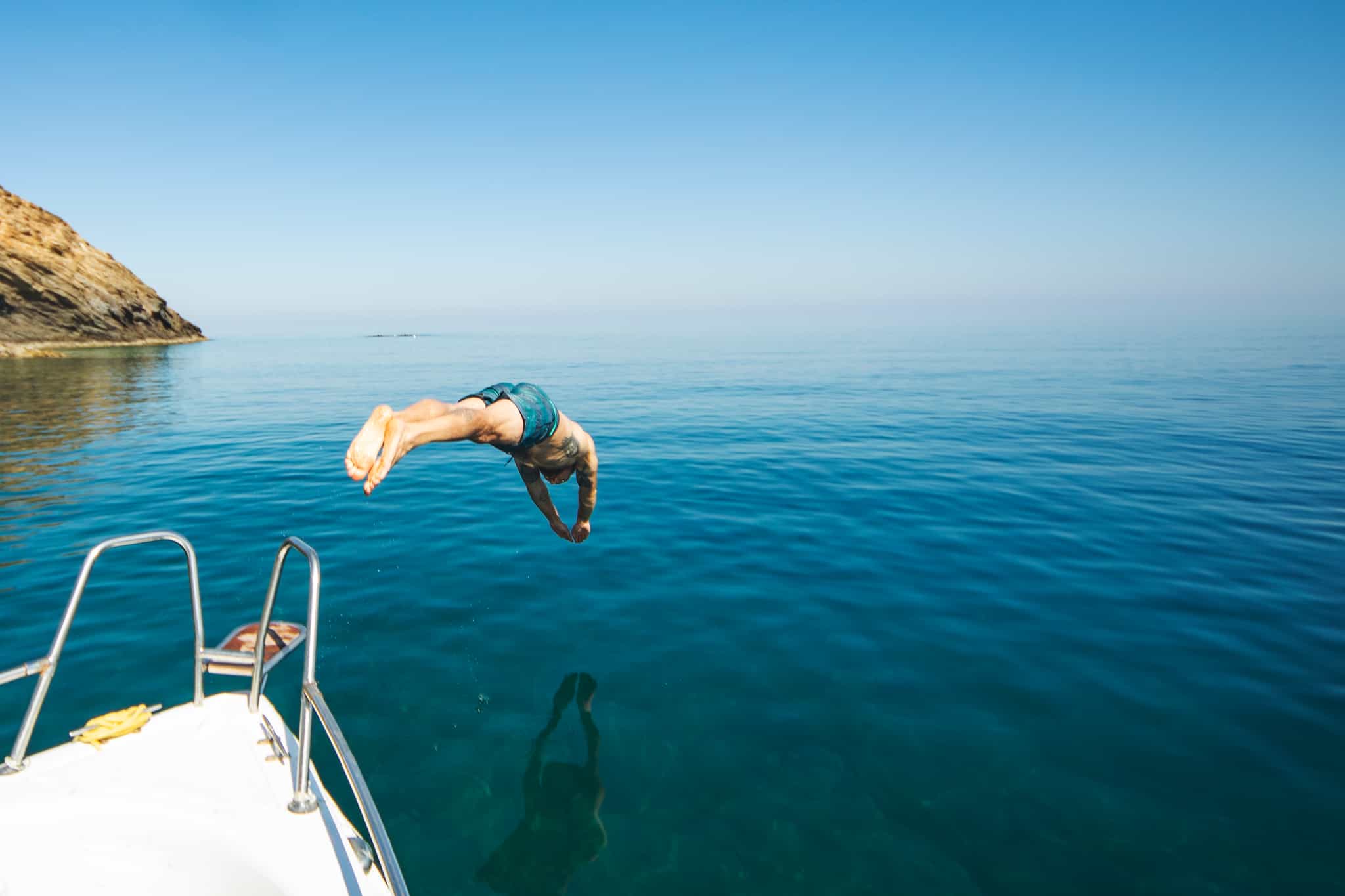 Man diving off a yacht in the Greek islands.