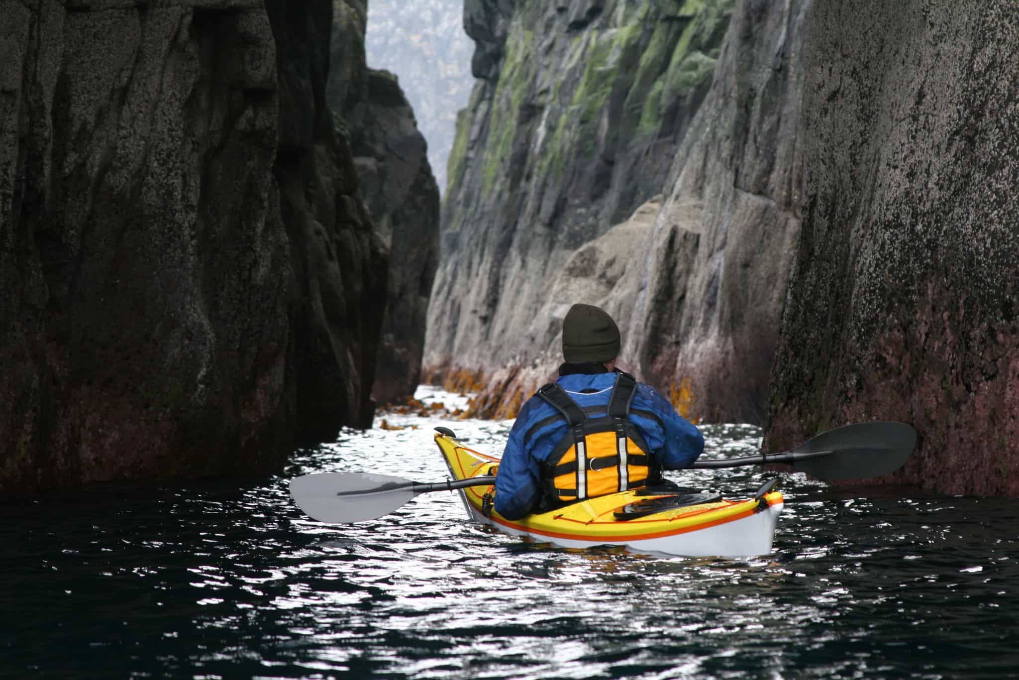 Sea Kayaker at cliff arch near Stac Buidhe, Skye, Scotland.