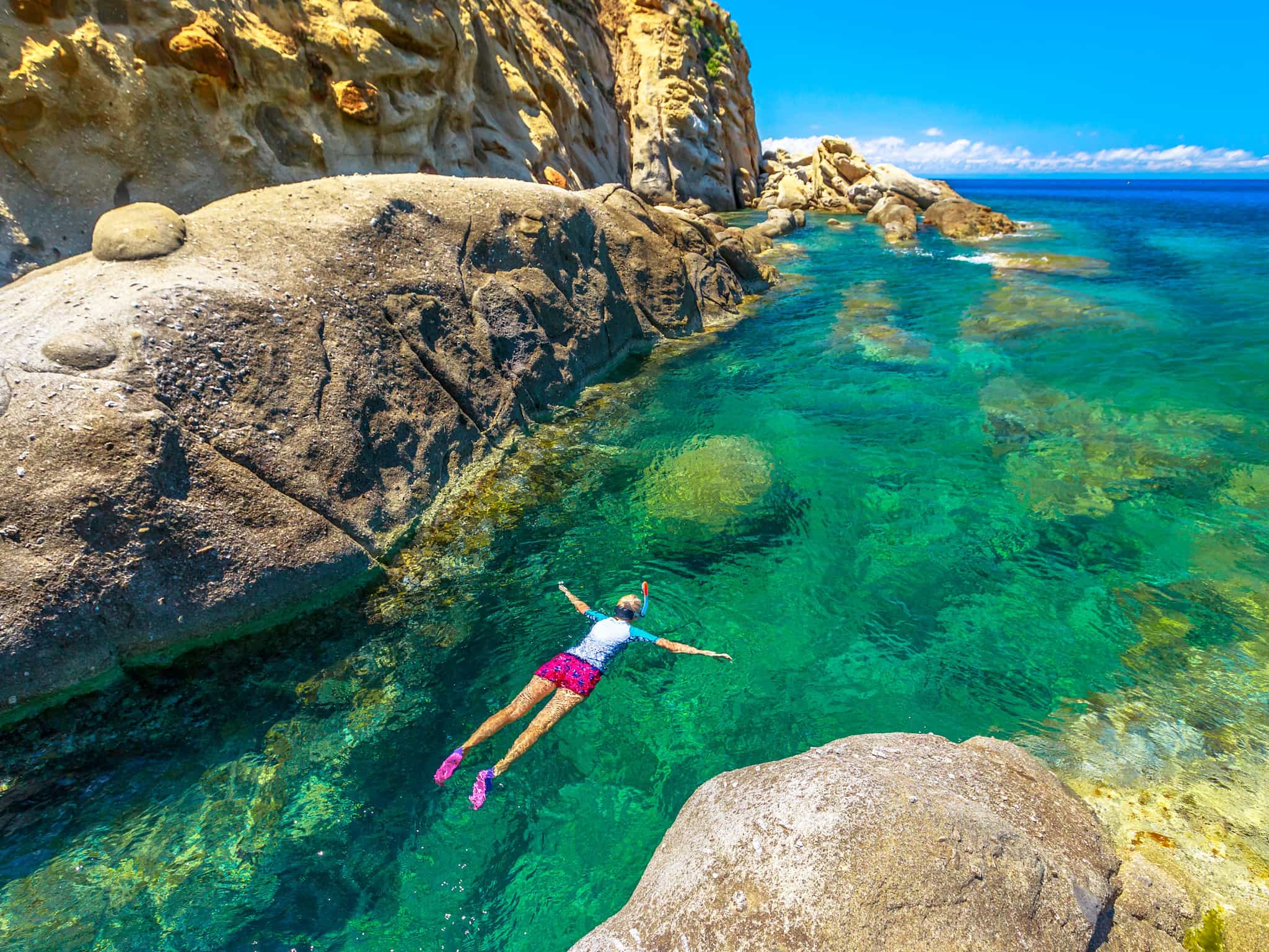 A woman snorkelling in turquoise waters off Elba's Sant'Andrea Beach in Italy.