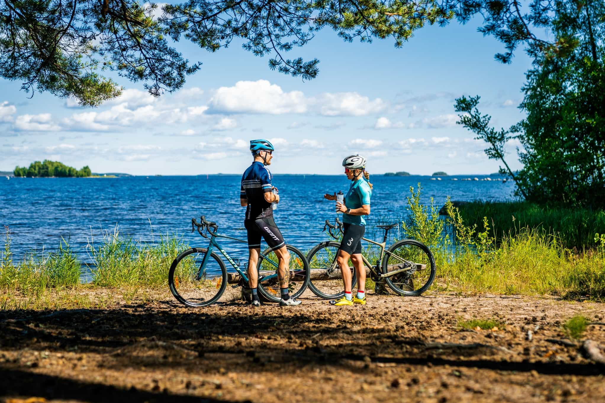 Two cyclists stopping for a break on the shores of Lake Saimaa