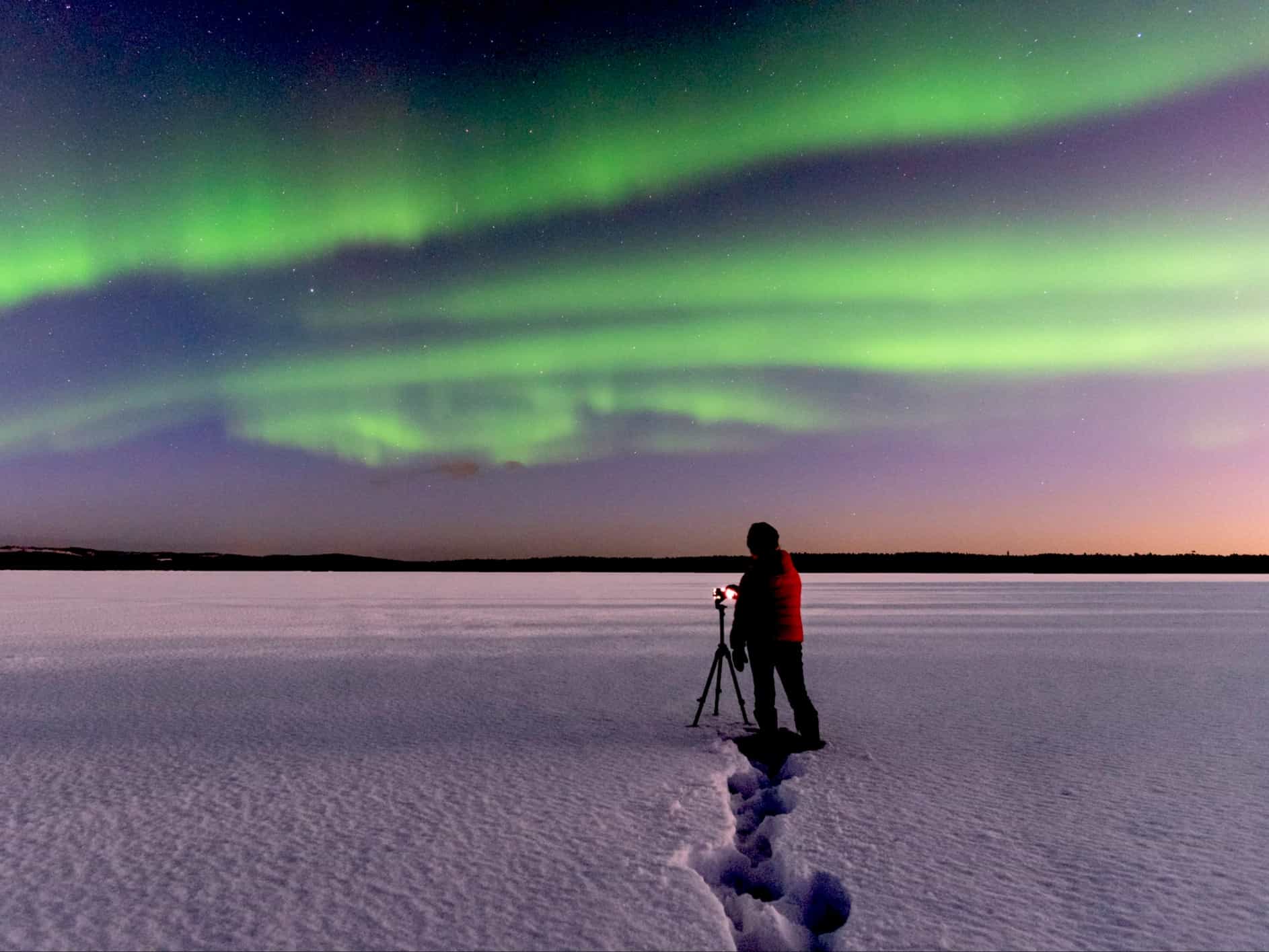 Man taking photos of the northern lights with tripod in Lapland.