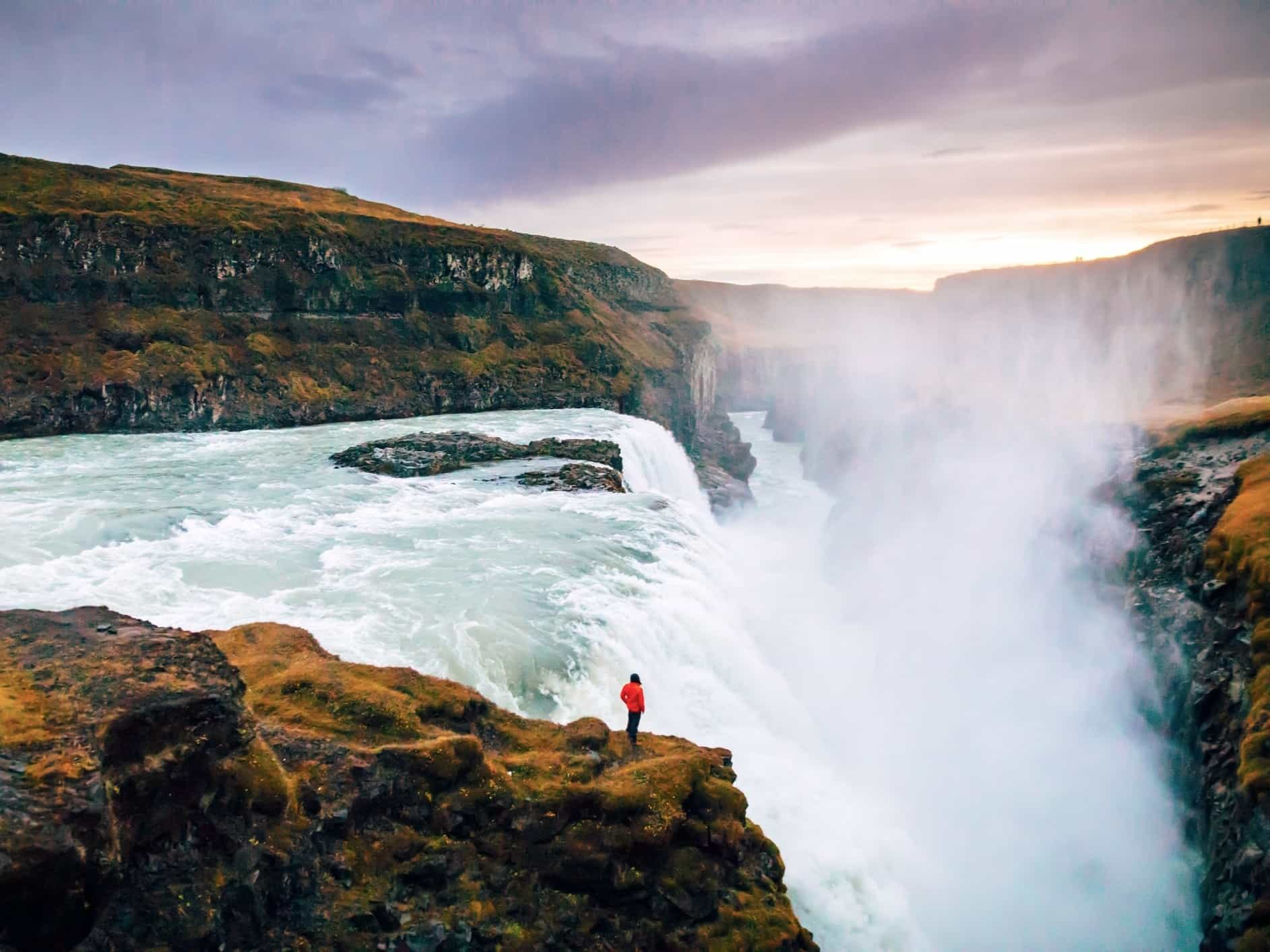 Person standing at the dramatic Gullfoss waterfall in Iceland, Photo: GettyImages-1058738610
