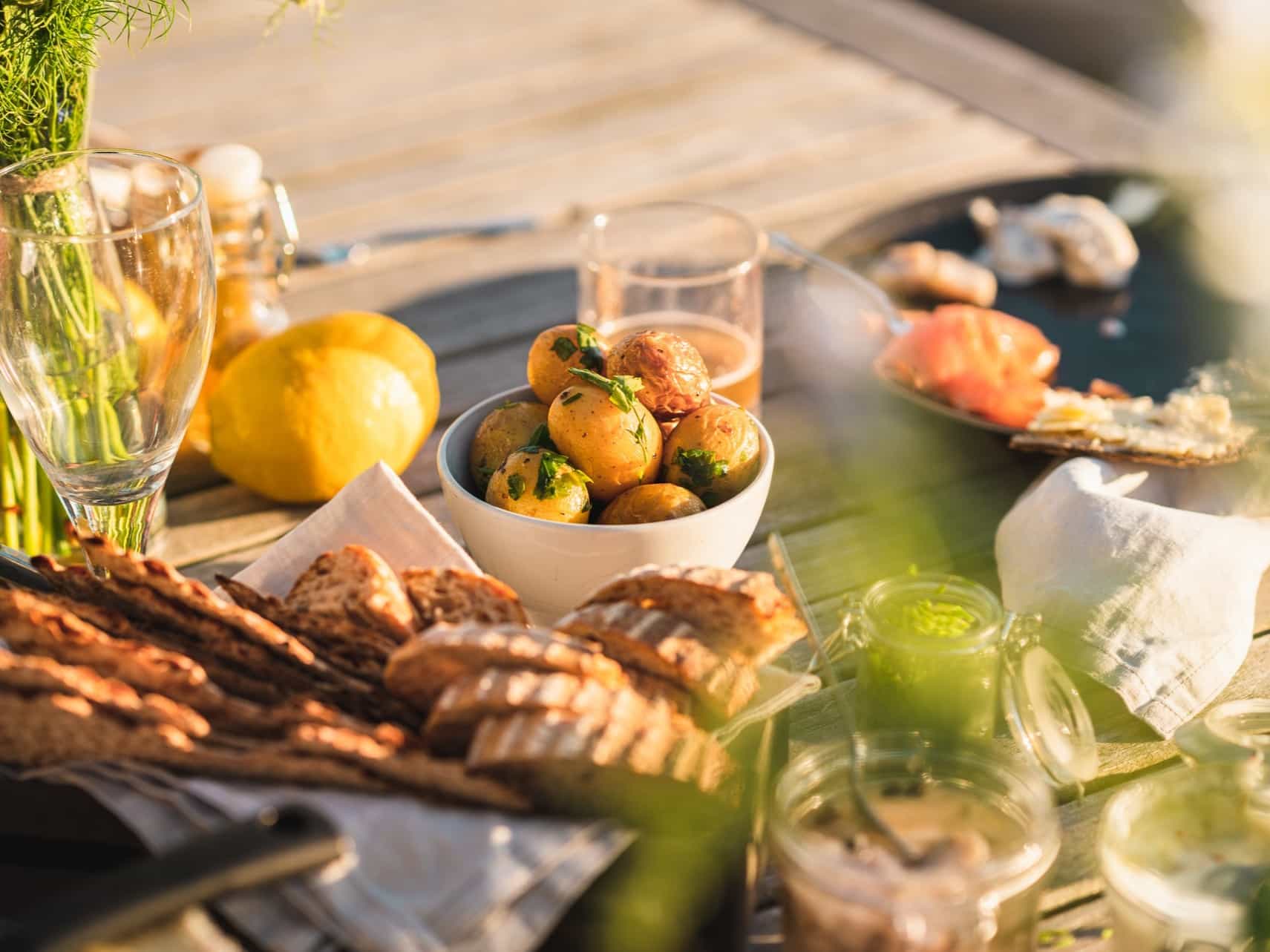 Wooden table with food laid including lemons, potatoes and bread