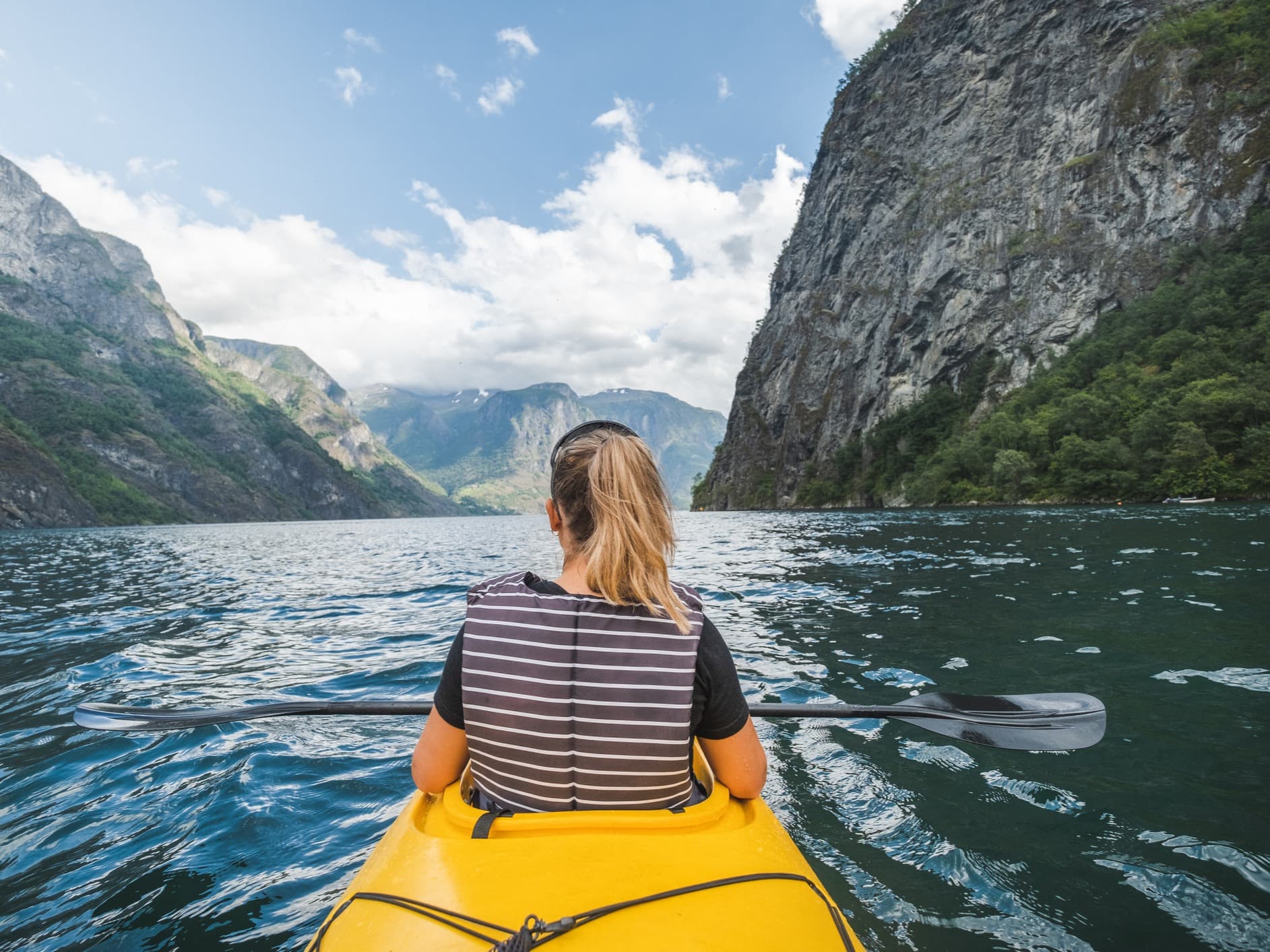 A woman paddles through the Naeroyfjord in the Norwegian Fjords.
