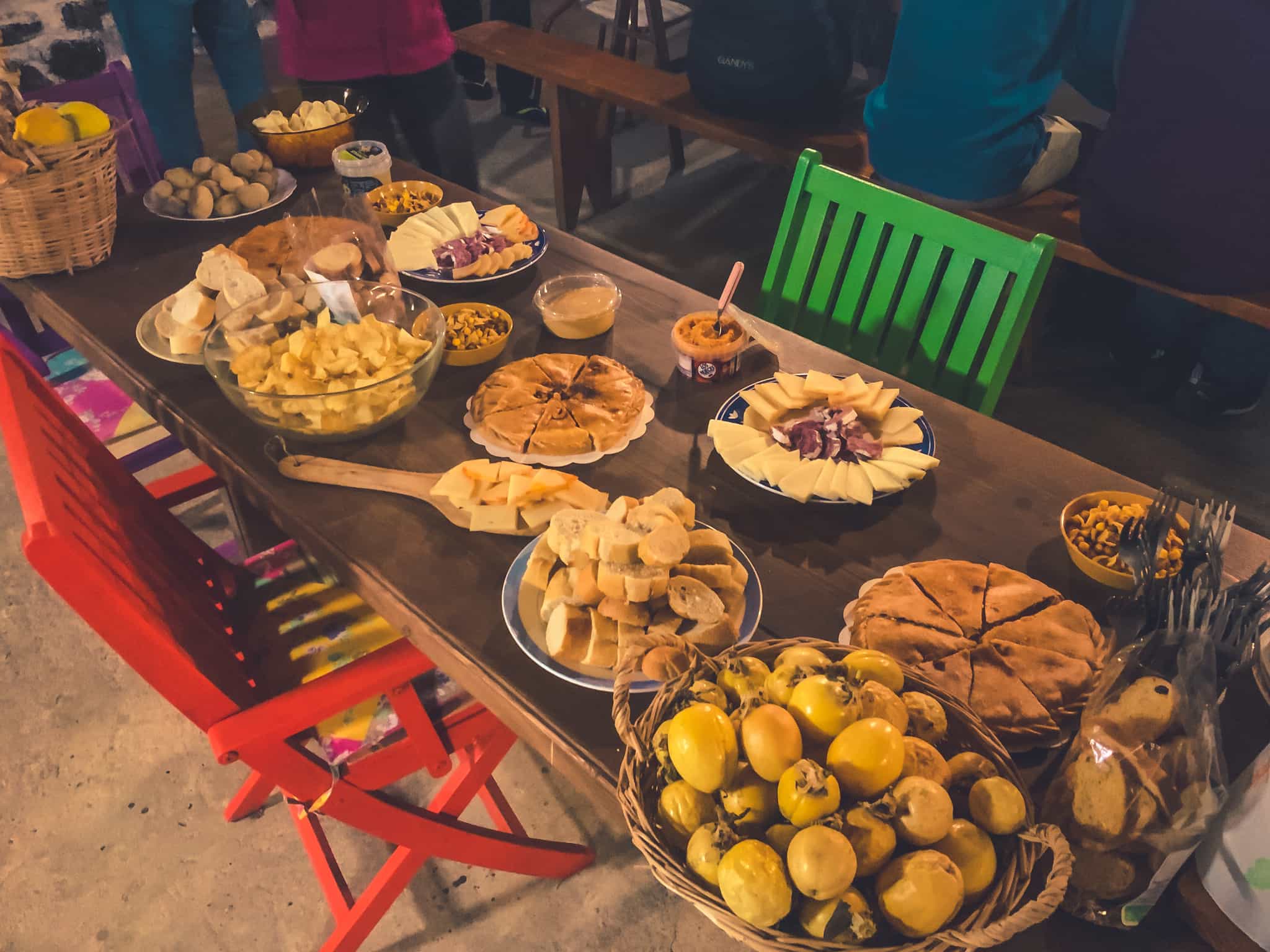 A spread of Canarian dishes on a long table including cheeses, breads, tortilla and fruit.