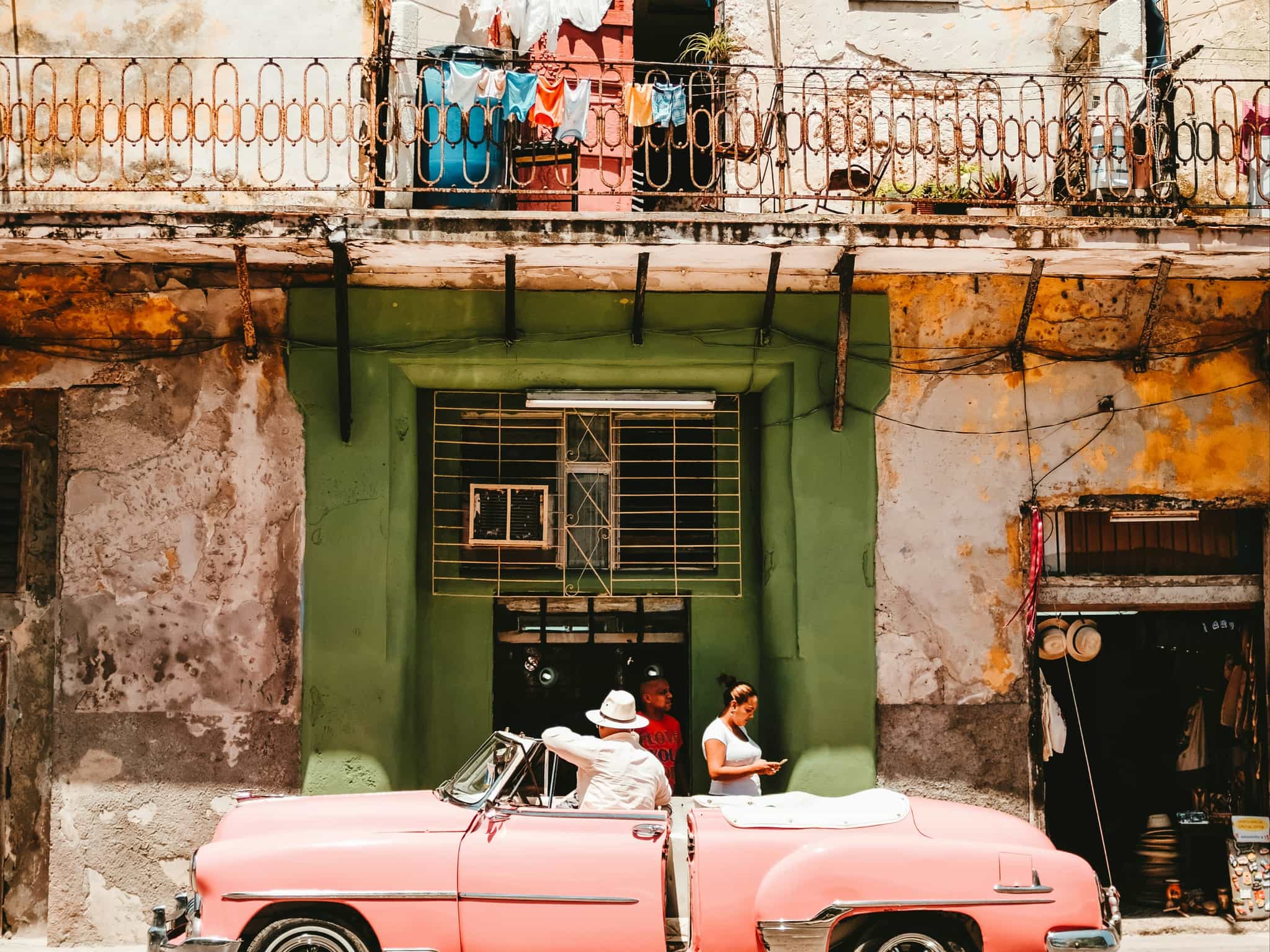 Person standing beside of pink vintage, convertible car in Cuba, Photo: stephan-valentin-qRBNM6GmXDE-unsplash