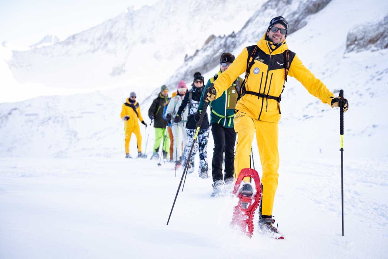 Line of smiling hikers with snowshoes in the Dolomites, Italy.