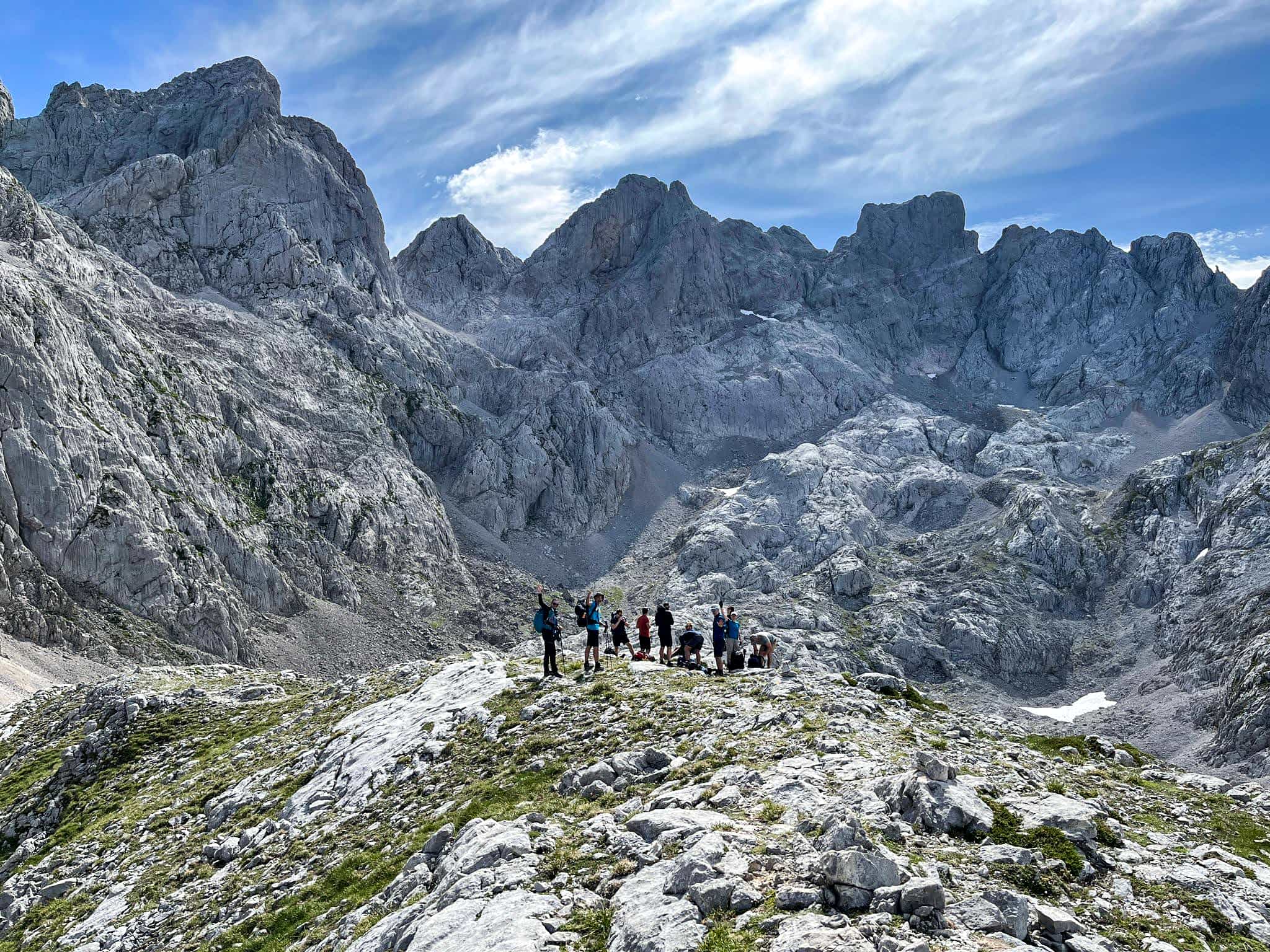 A group of hikers in the Picos de Europa backed by limestone mountains.