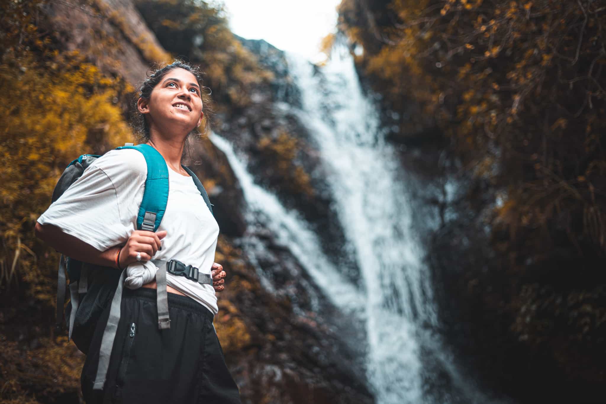 Hiker passing a forest waterfall, India. Photo: GettyImages-1273427592