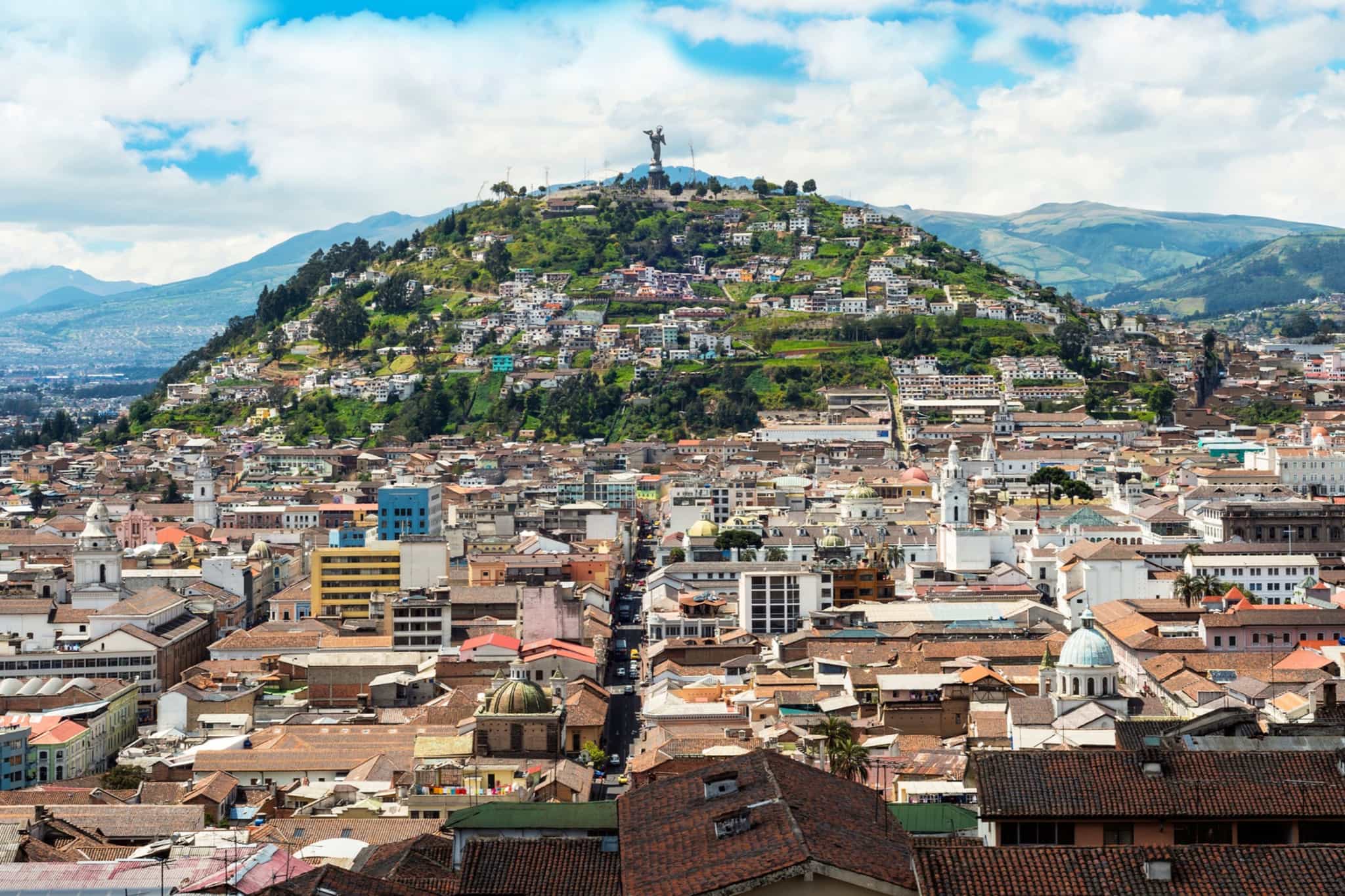 A city scape of Quito with the Virgen de El Panecillo statue standing proud in the background.