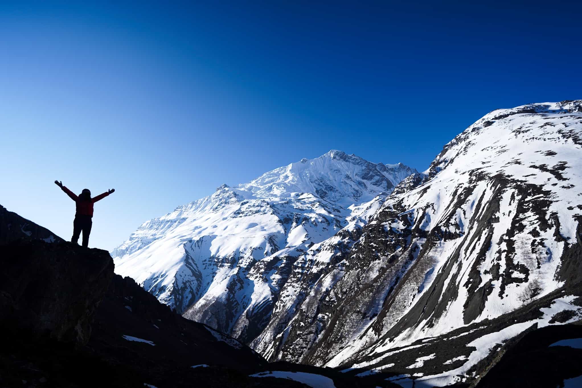 Silhouette of person with arms spread high at Tilicho Base Camp, Nepal.