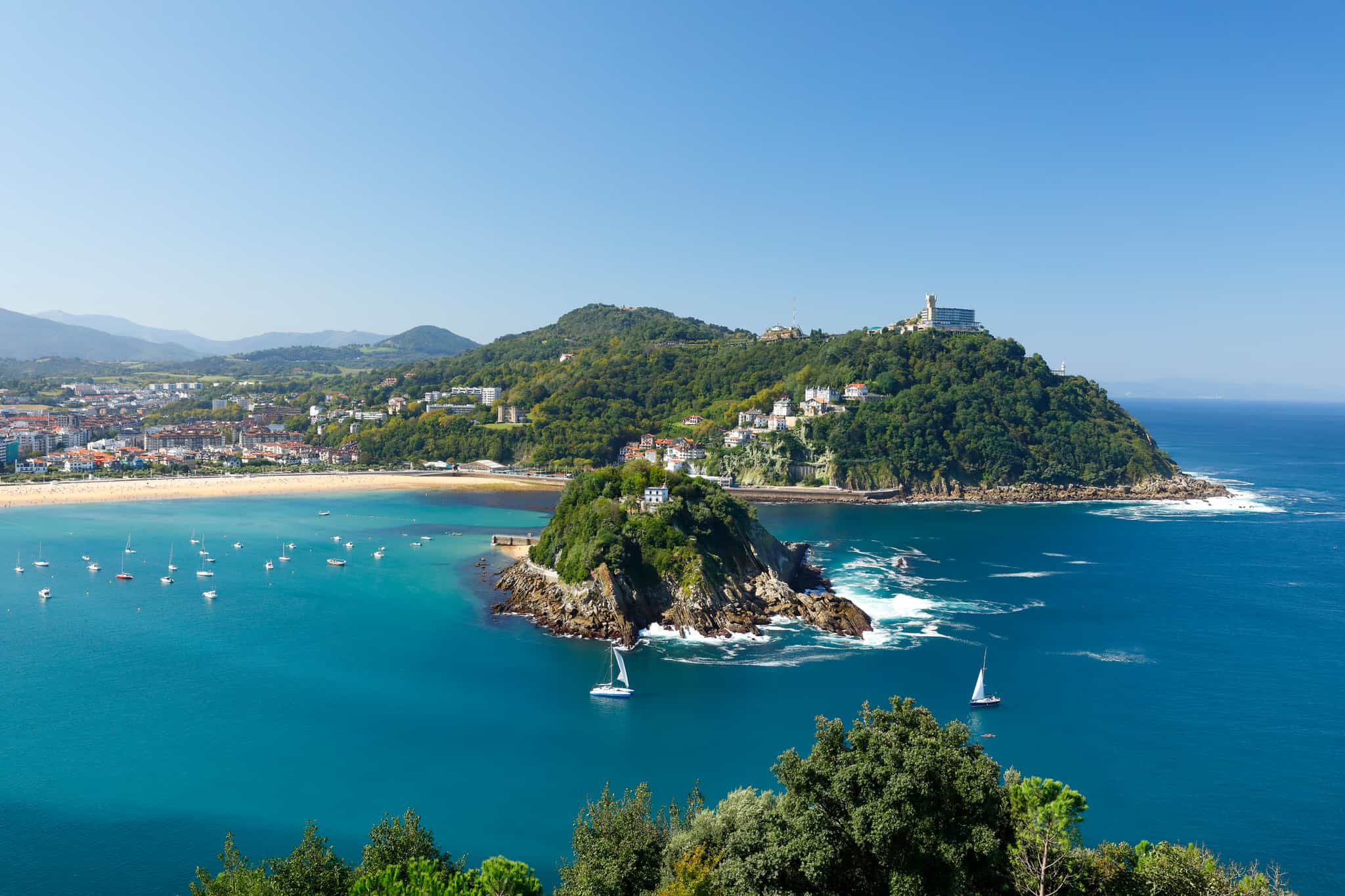 Sailing boats crossing Santa Clara island, San Sebastian, Spain