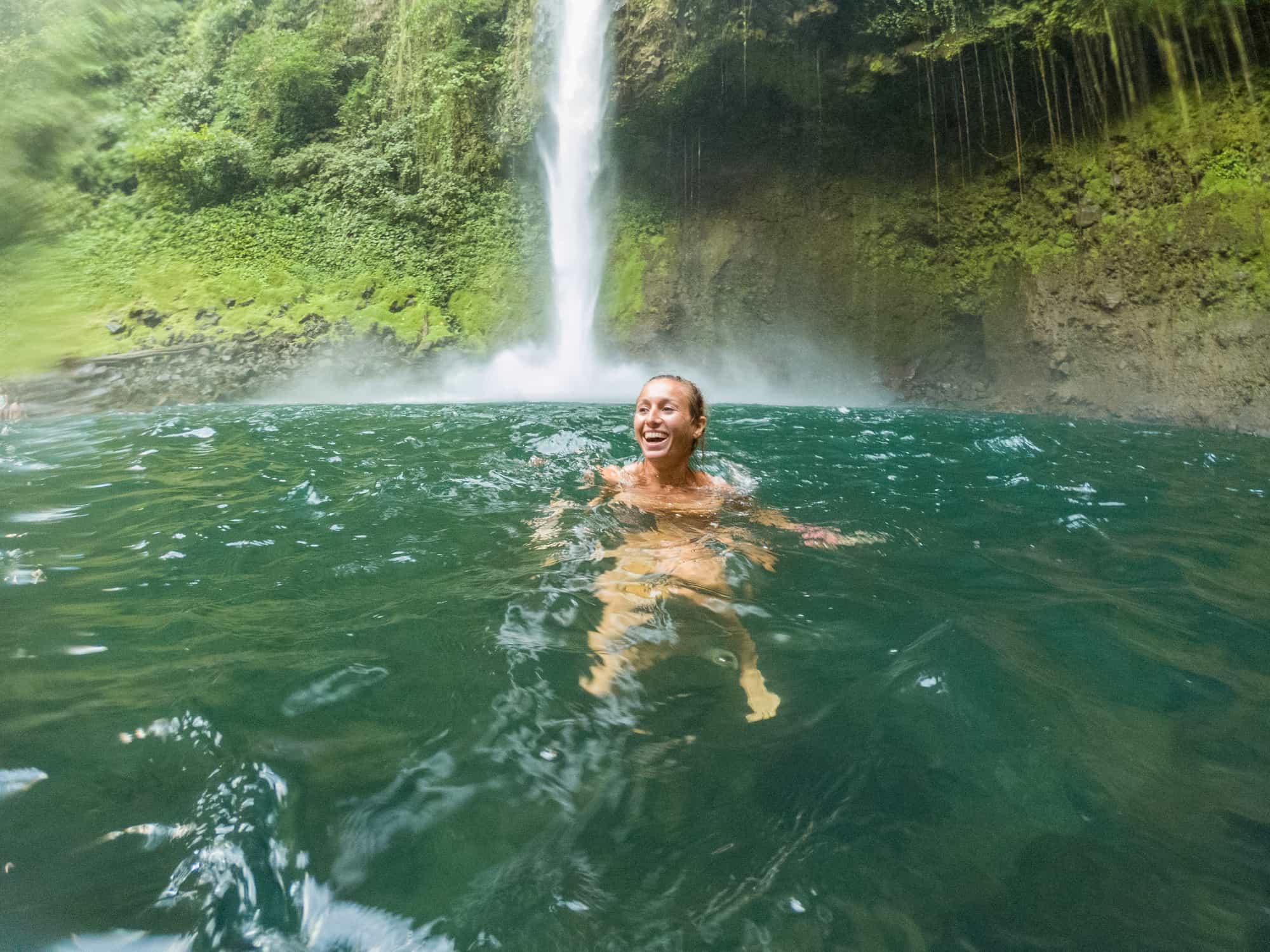 Young woman swimming in waterfall in Costa Rica